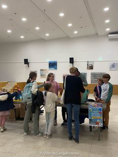 Stand de la collecte de dons tenu par le Conseil Municipal des Enfants en salle des fêtes de l'Hôtel de Ville avec personnes qui viennent déposer leur dons. - Agrandir l'image, .JPG 103 Ko (fenêtre modale)