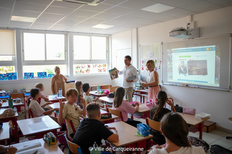 Photo de monsieur le Maire Arnaud Latil accompagné de Madame Laurence Meslard qui distribue les BD aux élèves de CM2 dans leur classe - Agrandir l'image, .PNG 1 Mo (fenêtre modale)
