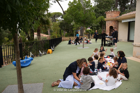 Photo des enfants qui prennent le pique-nique dans le jardin de la MMPE avec les animateurs de GRAC et le personnel de la crèche - Agrandir l'image, .PNG 2 Mo (fenêtre modale)