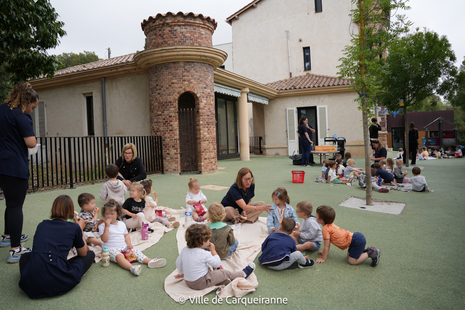 Photo des enfants qui prennent le pique-nique dans le jardin de la MMPE avec les animateurs de GRAC et le personnel de la crèche - Agrandir l'image, .PNG 2 Mo (fenêtre modale)