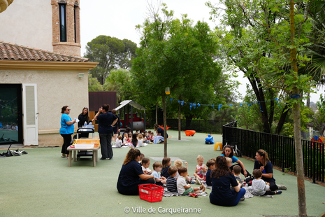 Photo des enfants qui prennent le pique-nique dans le jardin de la MMPE avec les animateurs de GRAC et le personnel de la crèche - Agrandir l'image, .PNG 2 Mo (fenêtre modale)